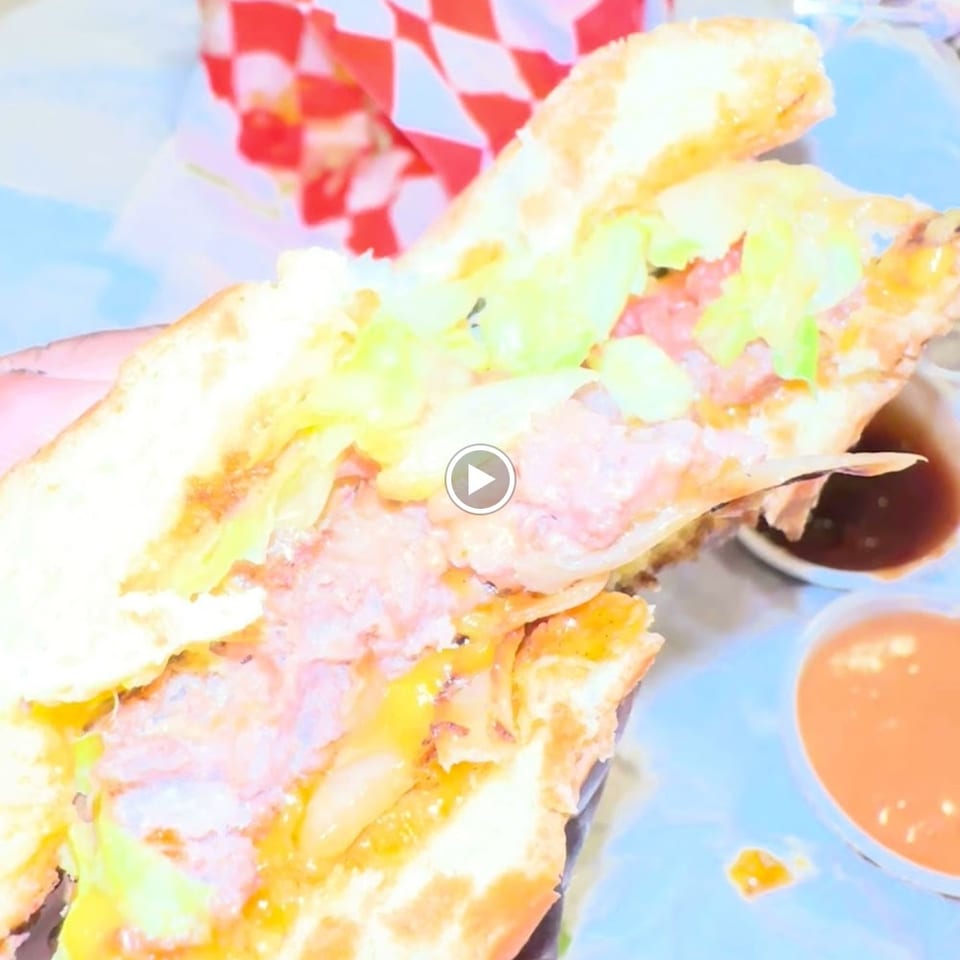 A close-up of a vegan burger from THE KRAZY VEGAN, with lettuce, cheese, and sauces.