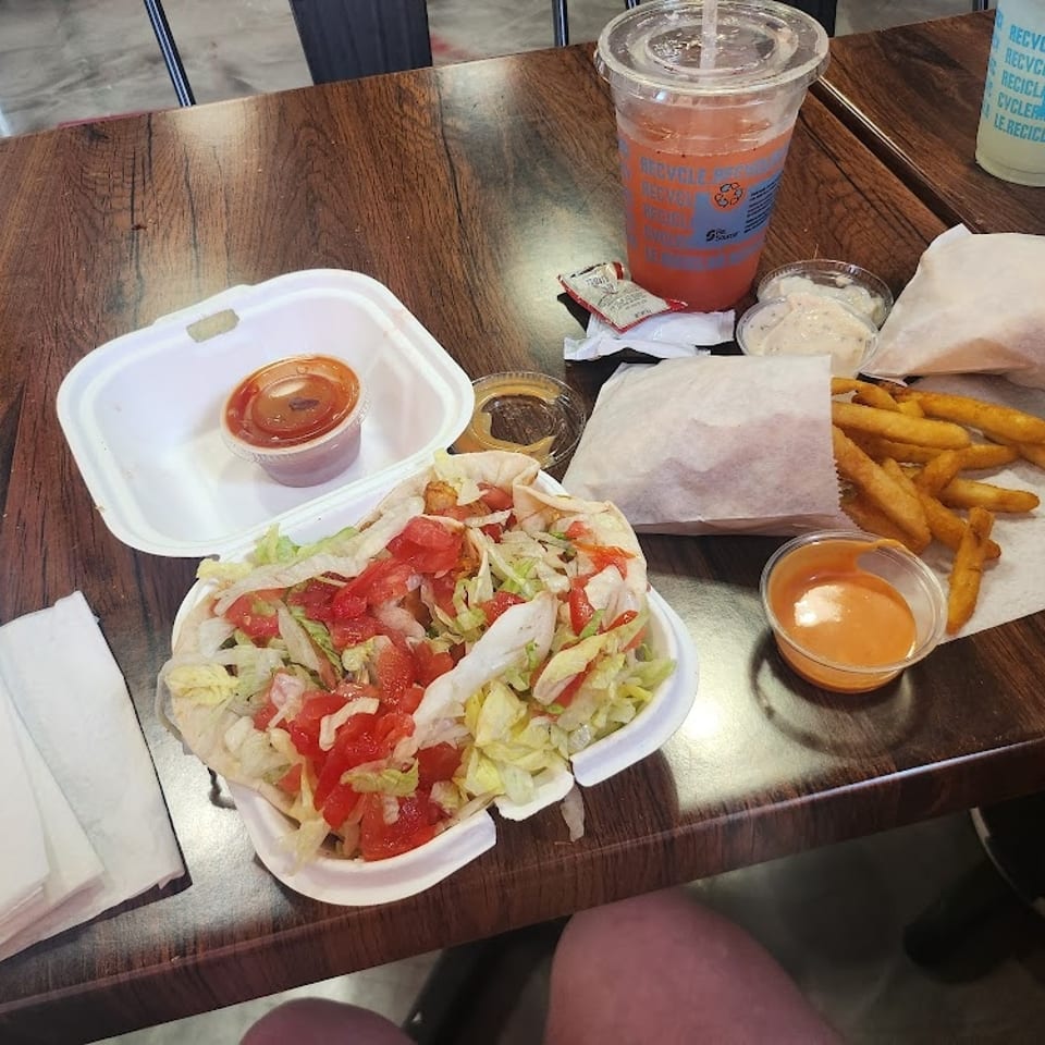 Vegan burger, fries, and drinks on a wooden table at THE KRAZY VEGAN.