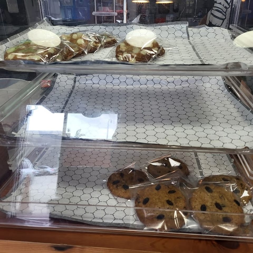 Vegan cookies, including chocolate chip and white chocolate macadamia, displayed in a clear case.